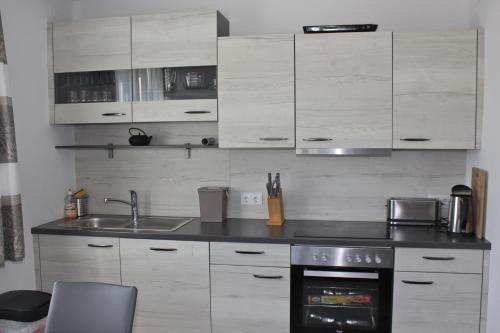 a kitchen with white cabinets and a sink at Haus Mup in Spittal an der Drau