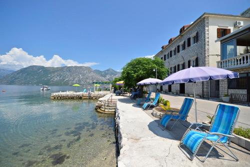 a row of chairs and umbrellas next to a body of water at Pana-Eustahije 253 in Kotor