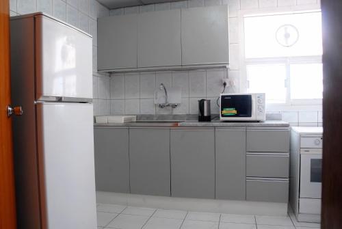 cocina blanca con nevera y microondas en Basma Residence Hotel Apartments, en Sharjah