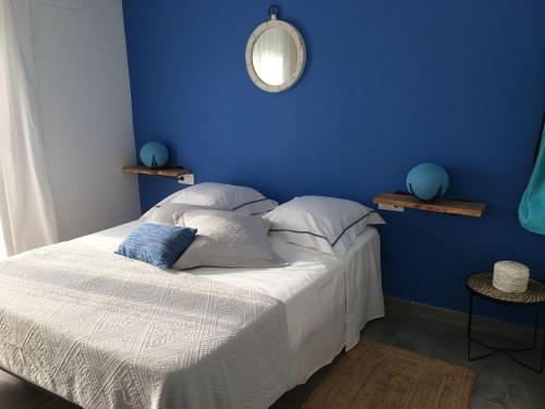 Un dormitorio con una pared azul y una cama con almohadas en Casa Sol y Luz - casa rural, en Carboneras