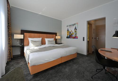 a bedroom with a large bed and a desk at Hotel & Living Am Wartturm in Speyer
