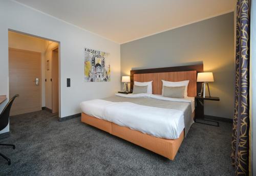 Habitación de hotel con cama grande y escritorio. en Hotel & Living Am Wartturm - Hotel & Apartments, en Speyer