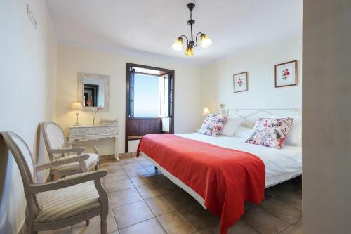 ein Schlafzimmer mit einem Bett mit einer roten Decke und einem Stuhl in der Unterkunft Villa La Malvasia in Fuencaliente de la Palma