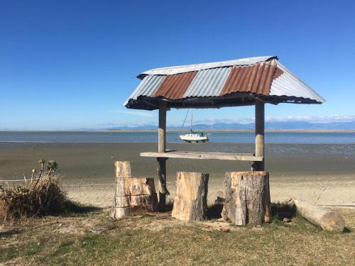 a picnic table on the beach with a boat on it at Glenwai in Motueka