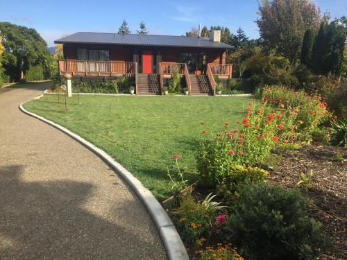 a house with a pathway leading to a yard with flowers at Glenwai in Motueka