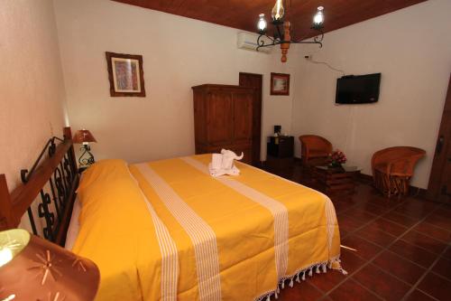 ein Schlafzimmer mit einem Bett mit einer gelben Decke in der Unterkunft Parador Monte Carmelo in Oaxaca de Juárez