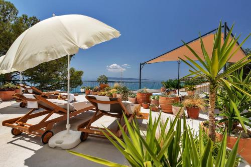 a patio with chairs and an umbrella and plants at Apartment Chiara in Tučepi