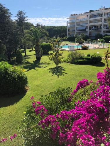 un parc avec des fleurs roses et un grand bâtiment dans l'établissement French Riviera Deluxe near Nice airport, à Cagnes-sur-Mer