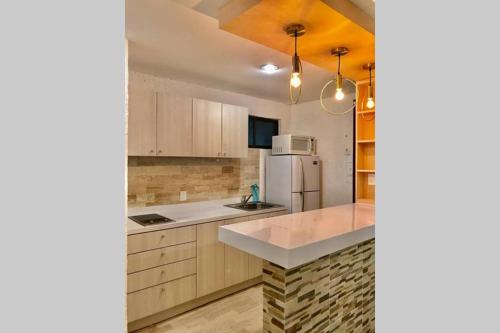a kitchen with wooden cabinets and a white refrigerator at Tu DEPA en el Paraíso Cancún 2 in Cancún