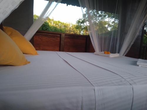 a bedroom with a white bed with a window at Dambulla Tree House in Dambulla