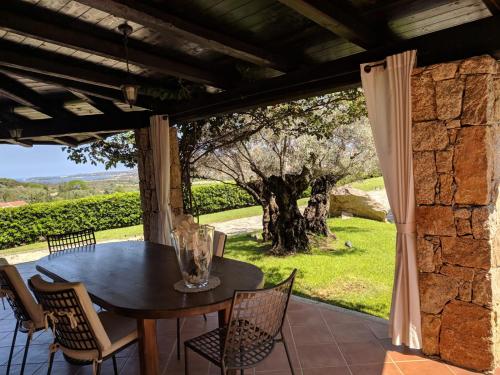 a table and chairs on a patio with a tree at Costa Smeralda House in Cugnana