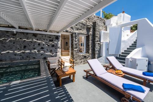 a patio with white chairs and a swimming pool at Iatis View Collection in Imerovigli