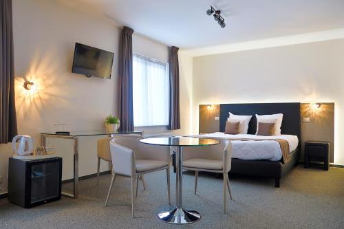 pokój hotelowy z łóżkiem, stołem i krzesłami w obiekcie Hotel Adoma w Gandawie