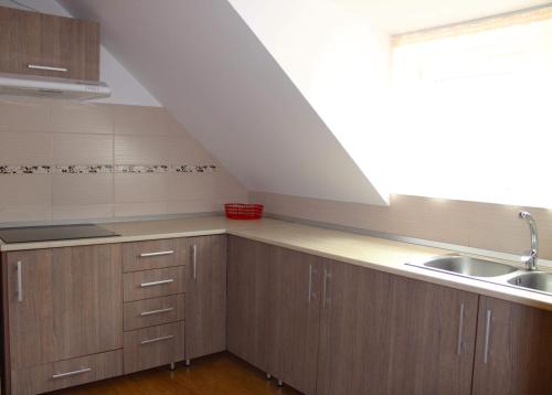an attic kitchen with wooden cabinets and a sink at Napsugár Vendégház in Sovata