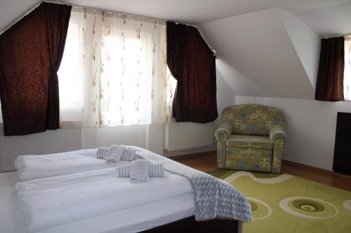 um quarto com uma cama, uma cadeira e uma janela em Napsugár Vendégház em Sovata