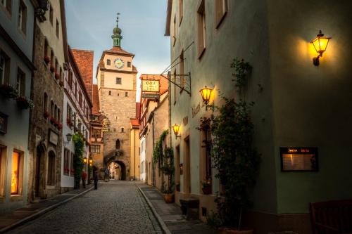 an alley in an old town with a clock tower at Gästehaus am weißen Turm in Rothenburg ob der Tauber