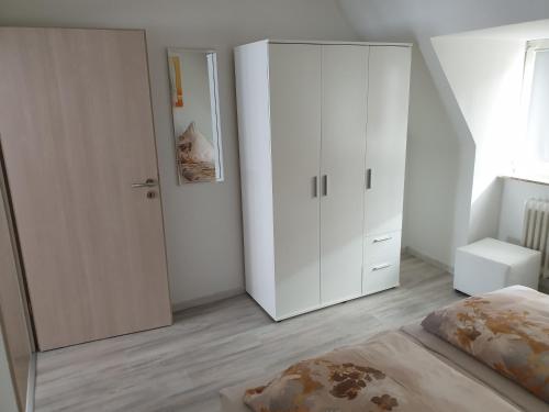 - une chambre avec une grande armoire blanche et un lit dans l'établissement Ferienwohnung Julia, à Emden