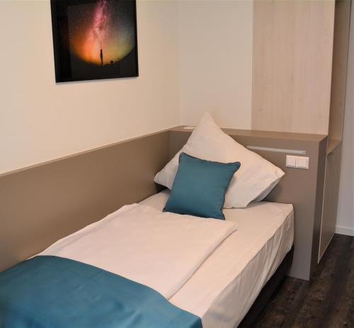 1 cama con 2 almohadas y una foto en la pared en Hotel BaWü en Stuttgart