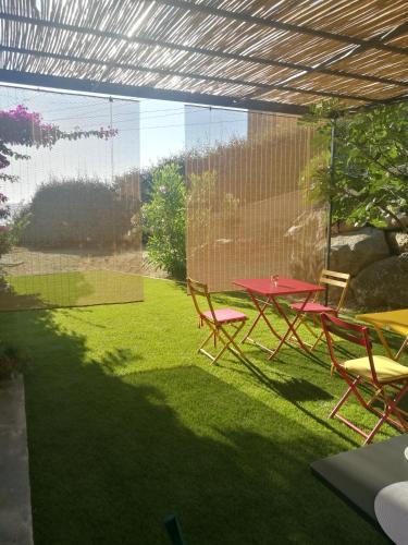 a patio with a table and chairs on the grass at Casa Peppina - Chez Tonio et Sylvie in Sari Solenzara
