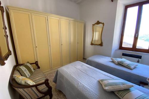 1 dormitorio con 2 camas, armario y silla en Casa Acquedotto Mediceo, en Pitigliano