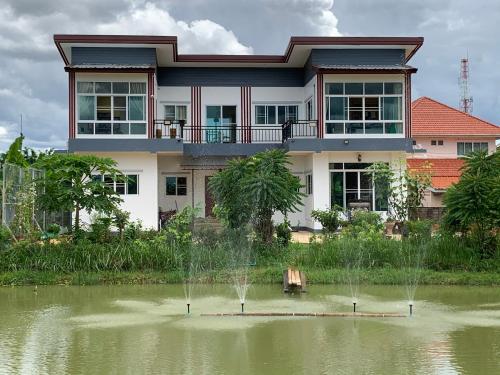 a house with a pond in front of a building at Open Kitchen in Chiang Rai