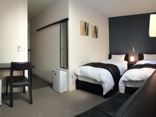 a hotel room with two beds and a chair at Value the Hotel Ishinomaki in Ishinomaki