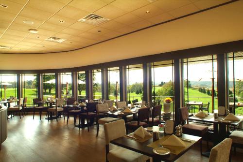 un comedor con mesas, sillas y ventanas en Inn at Lenape Heights-Golf Resort and Event Center, en Ford City