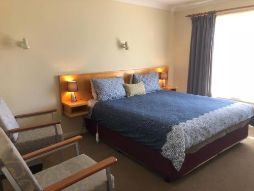 a bedroom with a bed and a chair and a window at Anna Bella Motel Glen Innes in Glen Innes