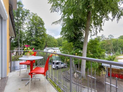 a balcony with red chairs and a table and a tree at Marie_3 in Heringsdorf