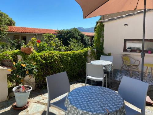 a patio with a table and chairs and an umbrella at Casa Orfea in Algajola