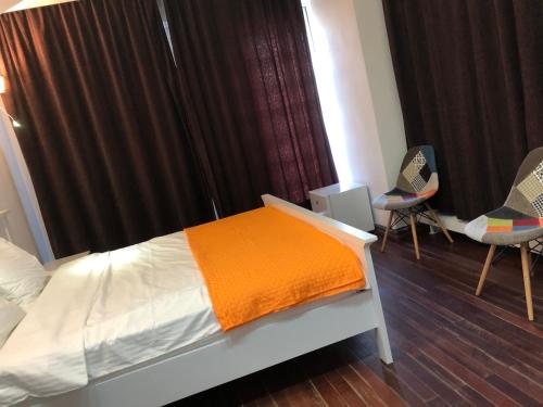 a bedroom with a bed with an orange blanket and two chairs at Pensiunea Pont-Euxin in Constanţa