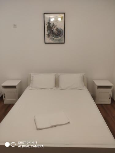 1 dormitorio con 1 cama blanca y 2 mesitas de noche en Casa Salomiea, en Eforie Nord