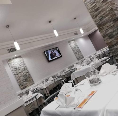 a dining room with white tables and chairs and a television at Central Park in Casarile