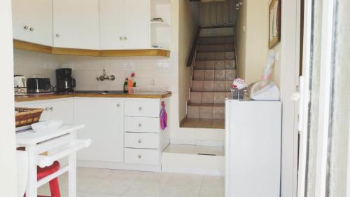 uma cozinha com armários brancos e uma escadaria em Efi's Cottage by the sea em Fiskardo
