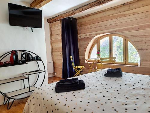 une chambre avec un lit, une télévision et une fenêtre dans l'établissement La maison basse, à Saint-Dalmas-le-Selvage