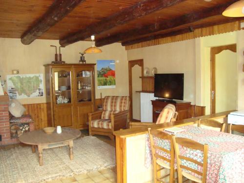 un salon avec une table et une télévision dans l'établissement CHARMANTE MAISON A LA CAMPAGNE AU COEUR DES PREMIERS VOLCANS, à Mézères