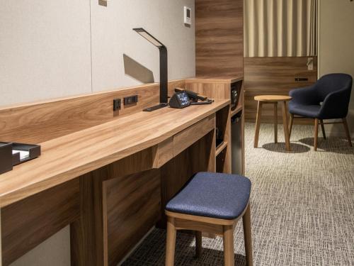 a reception desk with a blue stool and two chairs at Far East Village Hotel Tokyo Ariake in Tokyo