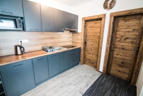 a kitchen with blue cabinets and a sink and a door at Apartmany JA&MA in Liptovský Mikuláš