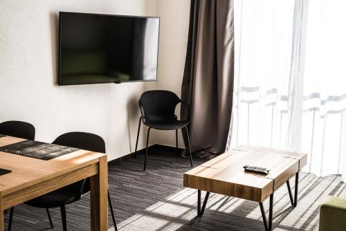 a room with a table and chairs and a flat screen tv at Apartmany JA&MA in Liptovský Mikuláš