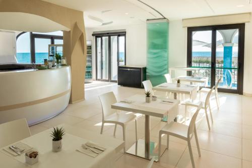a restaurant with white tables and chairs and the ocean at Life Hotel Seaview & Spa in Porto Recanati