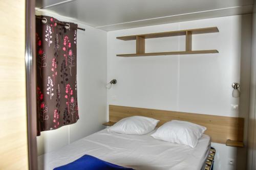 a bedroom with a bed with white sheets and pillows at Camping en Ardeche Le Lion in Bourg-Saint-Andéol