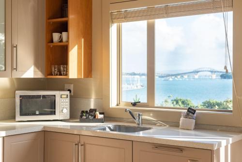 a kitchen with a microwave and a sink and a window at Ocean Breeze Hotel in Auckland