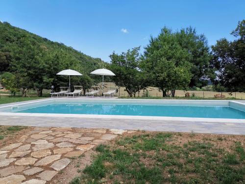 una piscina con sillas y sombrillas en un patio en La Sorgente del Radicino, en Semproniano