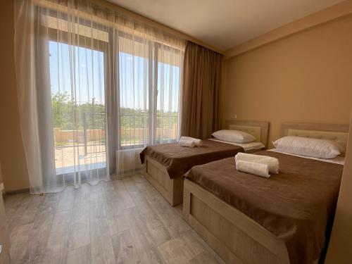 a hotel room with two beds and a large window at Lake House in Tskaltubo