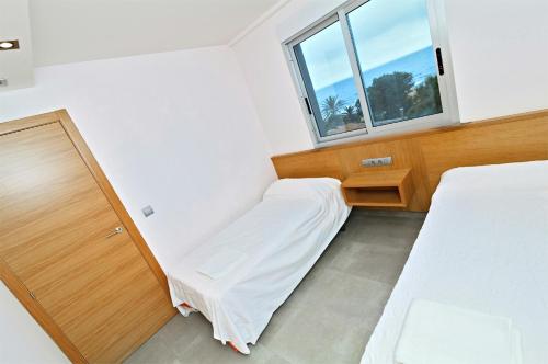デニアにあるApartamentos Bravosol VyBのベッド2台と窓が備わる小さな客室です。