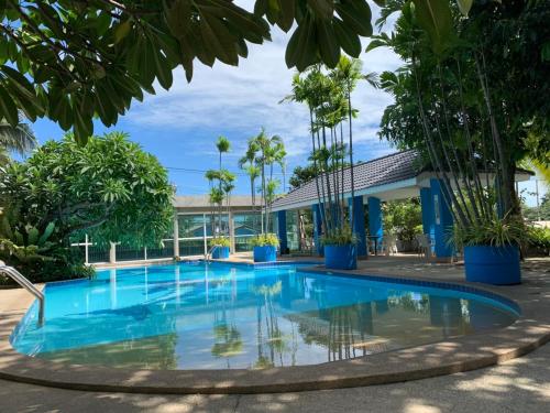 ジョムティエンビーチにあるBlue Garden Resort Pattayaのヤシの木が茂る建物の前にあるスイミングプール