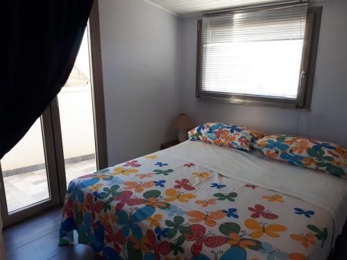 una camera da letto con un letto con copriletto floreale e 2 finestre di Casa vacanza Mansarda Sanleonina a Agrigento