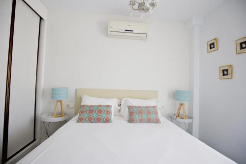 1 dormitorio con 1 cama blanca y 2 lámparas en La Marina Suite Málaga, en Málaga