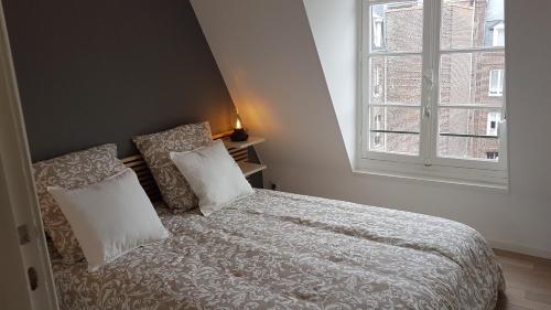 - une chambre avec un lit avec deux oreillers et une fenêtre dans l'établissement Quartier historique 100m plage WIFI, à Mers-les-Bains