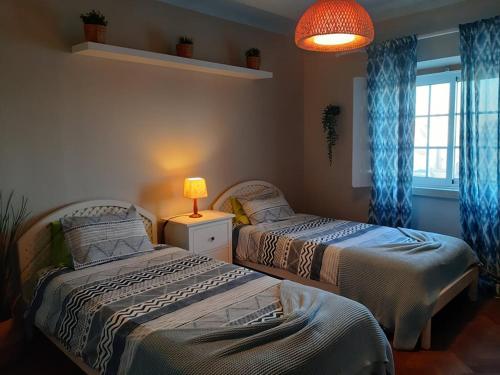 a bedroom with two beds and a lamp and a window at Casa Mestre Guesthouse in Vila do Bispo